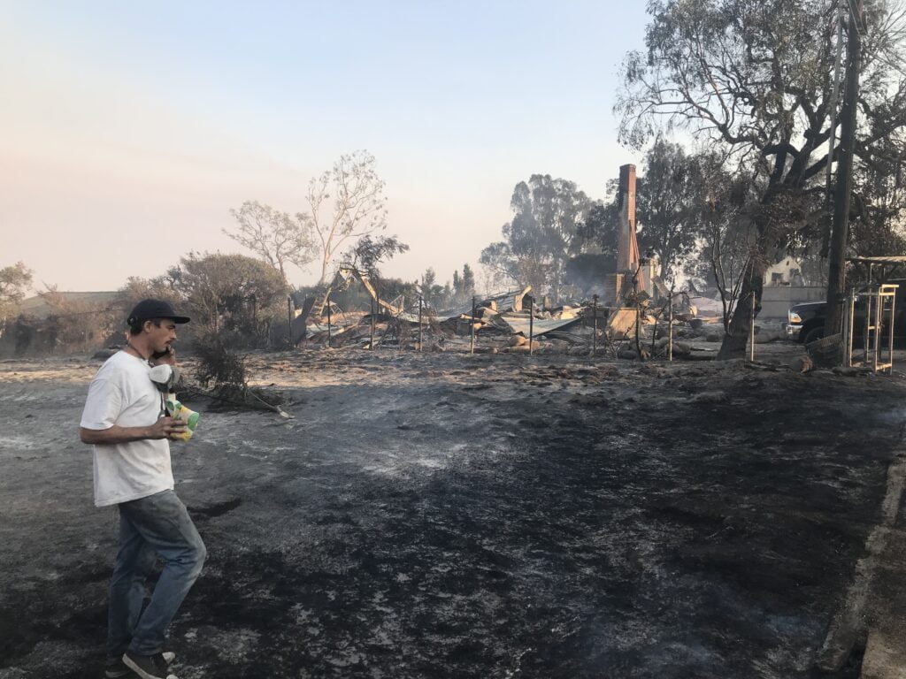 Keegan Gibbs with the remains of his family home in the background directly after the woolsey fire Photo credit Dru Jacobson