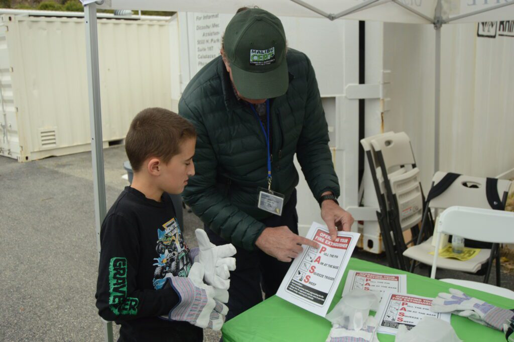 A Malibu CERT member walks Boonson Schmidt through fire extinguisher training at the Safety Expo on June 10